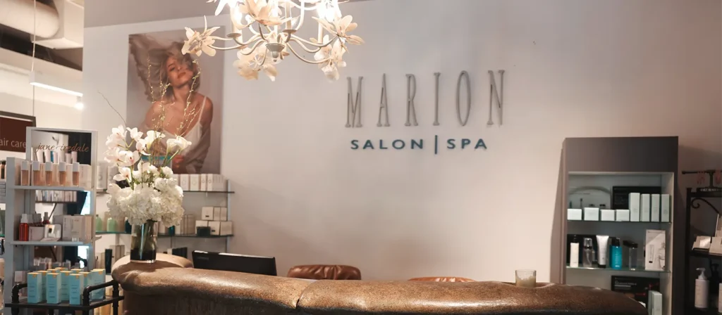 - Marion Salon Spa in Salt Point, NY Reception area of Marion Salon Spa with a flower chandelier, product shelves, a floral arrangement, and a portrait on the wall—creating an inviting space where guests can relax before enjoying treatments such as our deluxe hydrafacial skin treatment or booking an appointment for expert hand-tied hair extensions. - Marion Salon Spa in Salt Point, NY