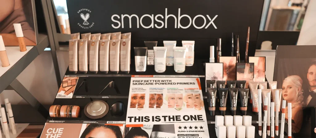 - Marion Salon Spa in Salt Point, NY Display of Smashbox makeup products including primers, foundations, powders, and eye products—perfect for pairing with volume eyelash extensions—for a complete look, all arranged on shelves with promotional signage in a retail setting. - Marion Salon Spa in Salt Point, NY