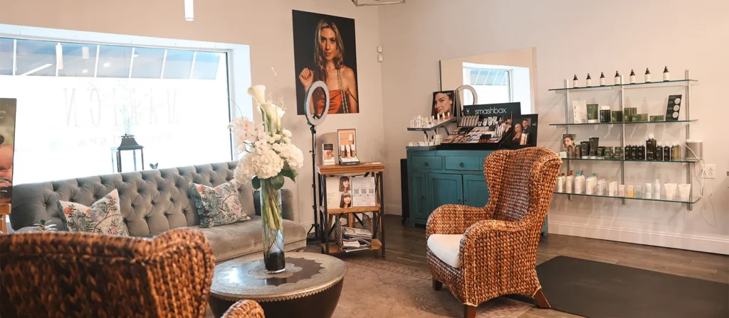 - Marion Salon Spa in Salt Point, NY A cozy salon waiting area with wicker chairs, a gray sofa, a coffee table with flowers, beauty products on shelves, and portraits on the walls offers a relaxing atmosphere where clients can unwind before their balayage hair color technique or deluxe hydrafacial skin treatment. - Marion Salon Spa in Salt Point, NY