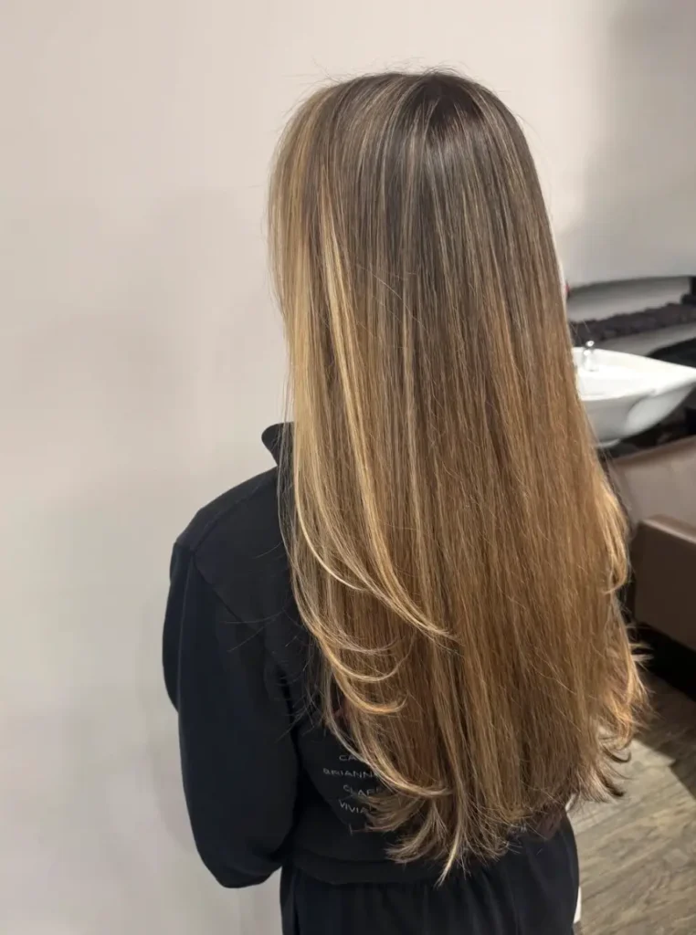 - Marion Salon Spa in Salt Point, NY Close-up of the back of a woman's sleek, straight hair with dark roots blending smoothly into warm golden-blonde ends, a signature result of the balayage hair color technique. - Marion Salon Spa in Salt Point, NY